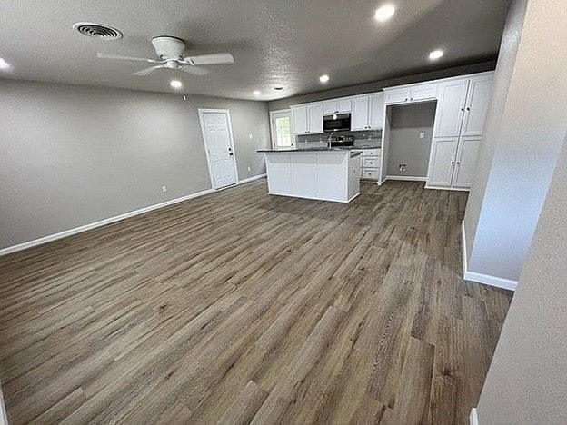 kitchen with dark hardwood / wood-style floors, white cabinetry, ceiling fan, and a kitchen island