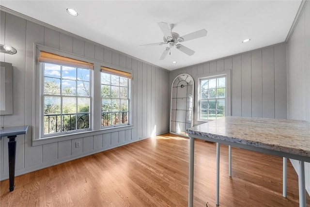 unfurnished office with ceiling fan, a healthy amount of sunlight, and light wood-type flooring