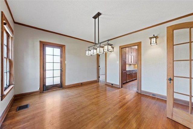 unfurnished dining area featuring ornamental molding and light hardwood / wood-style flooring