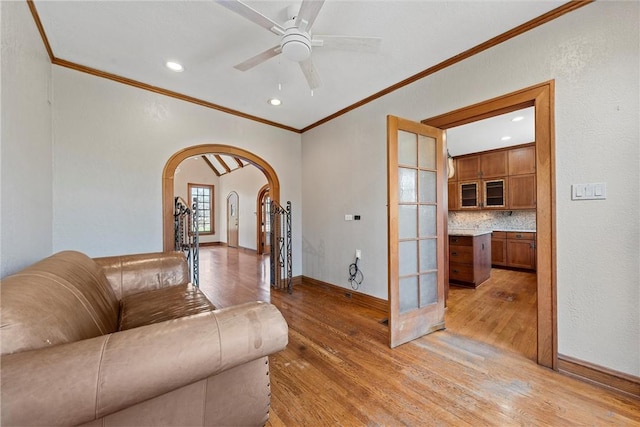 living room with ornamental molding, ceiling fan, and light wood-type flooring