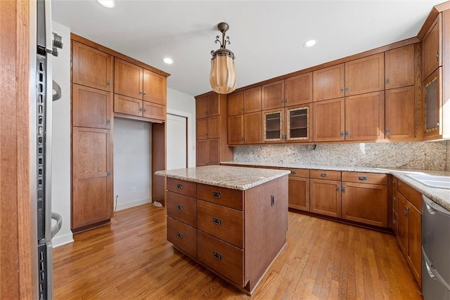 kitchen with pendant lighting, dishwasher, light stone counters, decorative backsplash, and light wood-type flooring