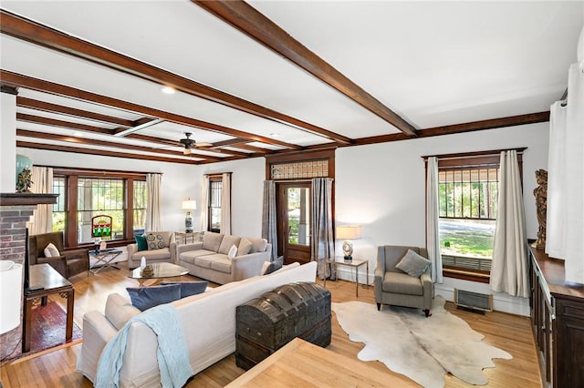 living room with beamed ceiling, a healthy amount of sunlight, and light wood-type flooring