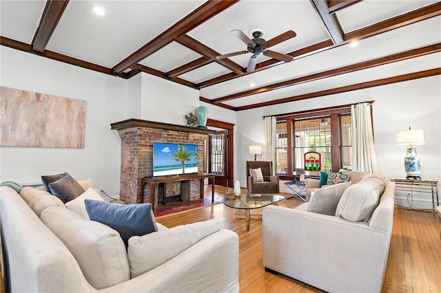 living room featuring ceiling fan, a fireplace, beamed ceiling, and light wood-type flooring