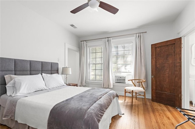 bedroom with light hardwood / wood-style flooring, ceiling fan, and cooling unit