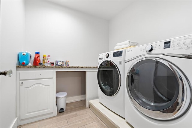 laundry area with washing machine and dryer and light wood-type flooring