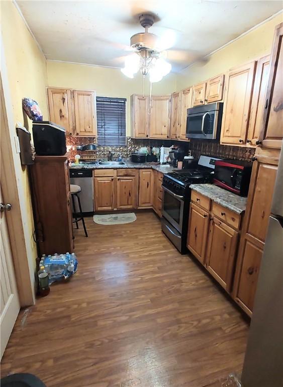 kitchen with dark hardwood / wood-style flooring, tasteful backsplash, stainless steel appliances, ceiling fan, and sink