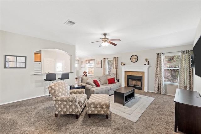 living room with carpet flooring, a tile fireplace, and ceiling fan