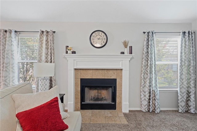 living room featuring a tiled fireplace, plenty of natural light, and light colored carpet