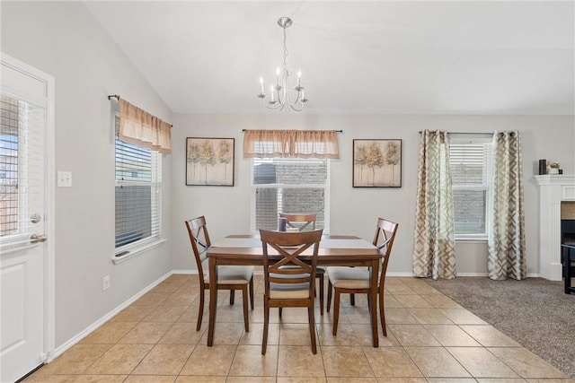 dining room with a notable chandelier, a healthy amount of sunlight, light colored carpet, and vaulted ceiling