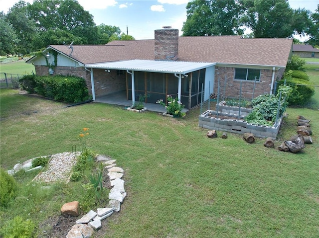 rear view of house with a sunroom and a lawn