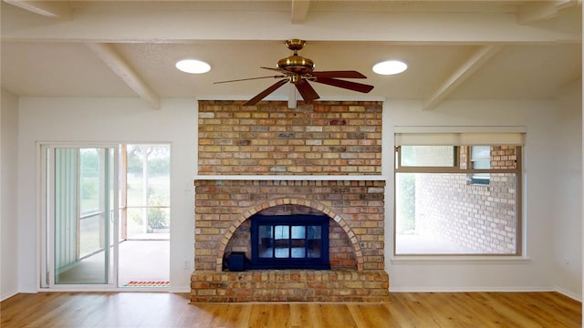 unfurnished living room with beamed ceiling, ceiling fan, hardwood / wood-style flooring, and a fireplace