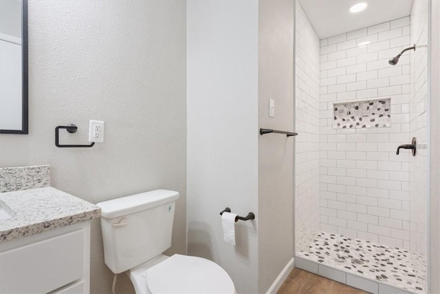 bathroom featuring tiled shower, vanity, and toilet