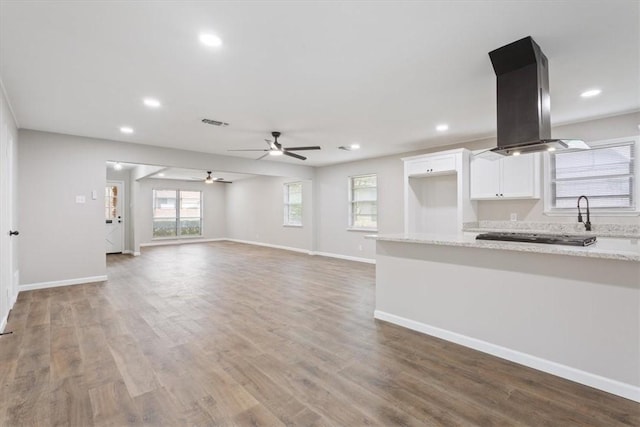 kitchen with ceiling fan, light stone countertops, white cabinetry, wood-type flooring, and island exhaust hood