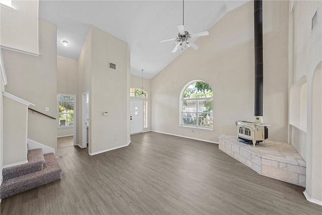 living room featuring high vaulted ceiling, a wood stove, plenty of natural light, and dark hardwood / wood-style floors