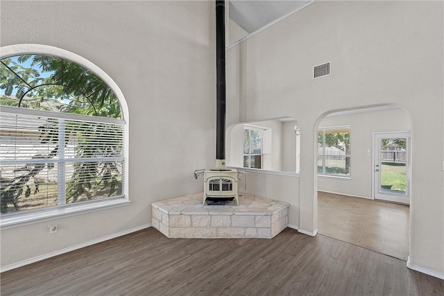 unfurnished living room with a wood stove, dark hardwood / wood-style flooring, and a high ceiling