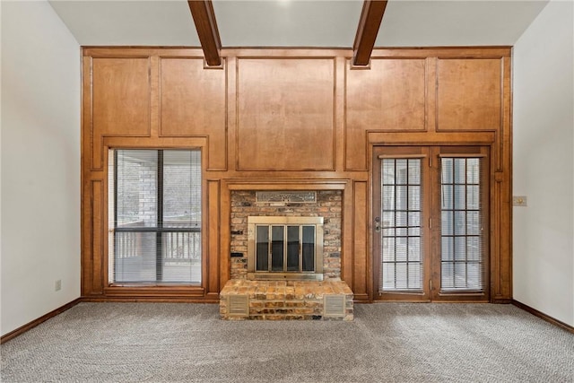 unfurnished living room with a brick fireplace, beam ceiling, baseboards, and carpet flooring