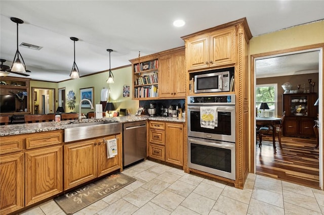 kitchen with appliances with stainless steel finishes, decorative light fixtures, sink, light stone counters, and light tile patterned floors