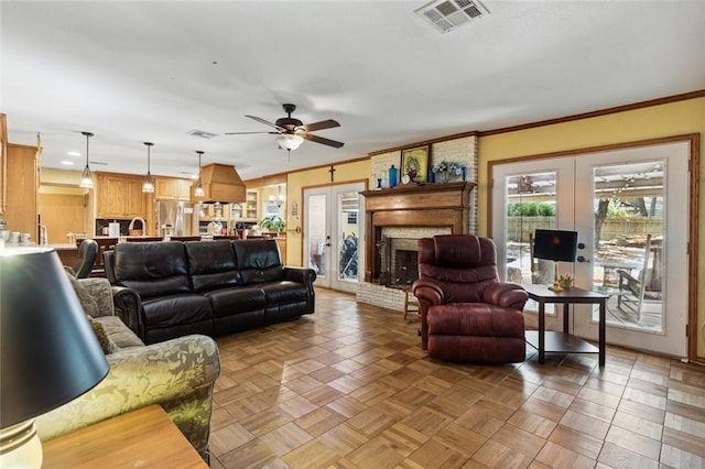 living room featuring a brick fireplace, french doors, parquet floors, ornamental molding, and ceiling fan