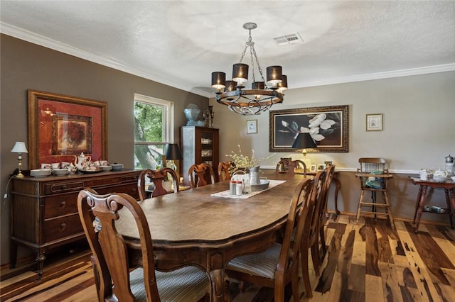 dining space with a notable chandelier, crown molding, a textured ceiling, and hardwood / wood-style floors