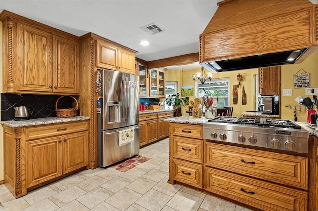 kitchen featuring a chandelier, light stone countertops, stainless steel appliances, and custom range hood