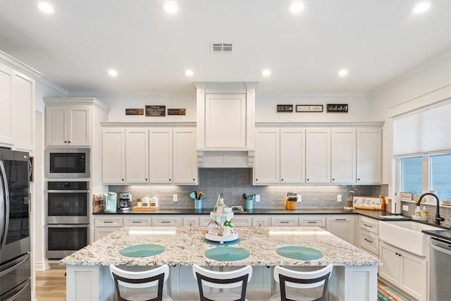 kitchen with appliances with stainless steel finishes, a kitchen bar, a sink, and crown molding