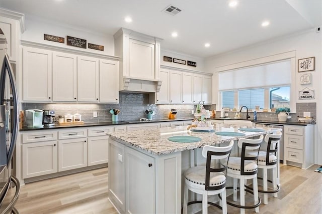 kitchen featuring refrigerator, visible vents, light wood-style flooring, white cabinetry, and a kitchen island