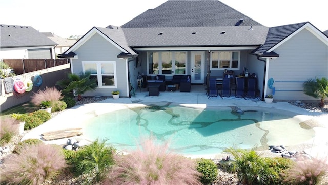 back of property featuring a patio, a shingled roof, fence, and a fenced in pool