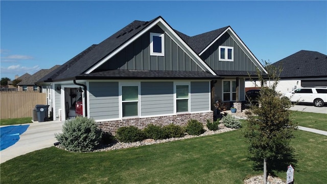 view of front of house featuring brick siding, fence, driveway, board and batten siding, and a front yard