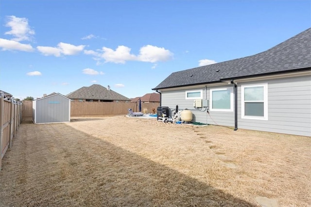 view of yard with a storage shed, a fenced backyard, and an outbuilding