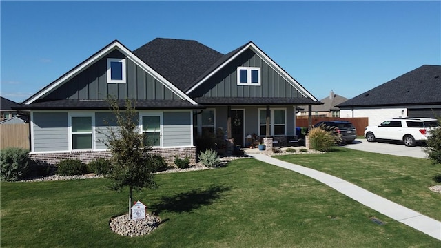 craftsman-style home with board and batten siding, brick siding, a front lawn, and roof with shingles