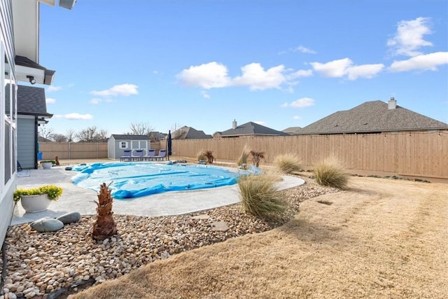 view of pool featuring a fenced in pool, a fenced backyard, a storage unit, an outdoor structure, and a patio area