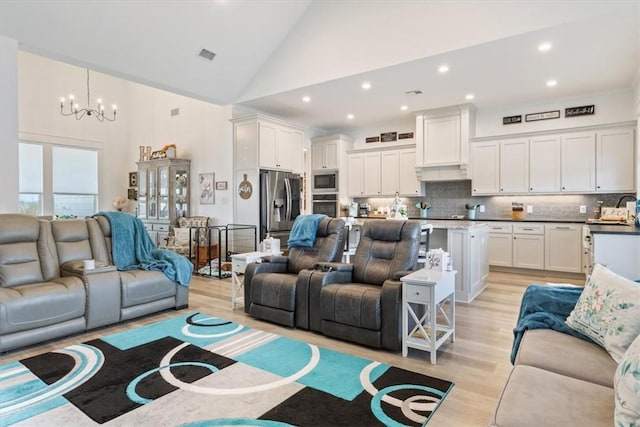 living area featuring light wood finished floors, visible vents, an inviting chandelier, high vaulted ceiling, and recessed lighting