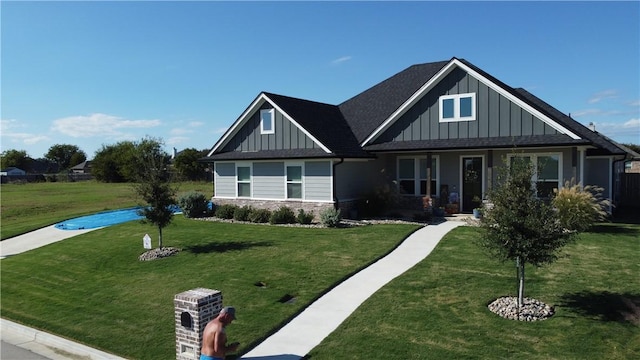 craftsman inspired home featuring covered porch, stone siding, a front lawn, and board and batten siding