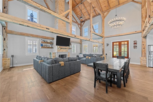 living room with high vaulted ceiling, french doors, a notable chandelier, and a fireplace