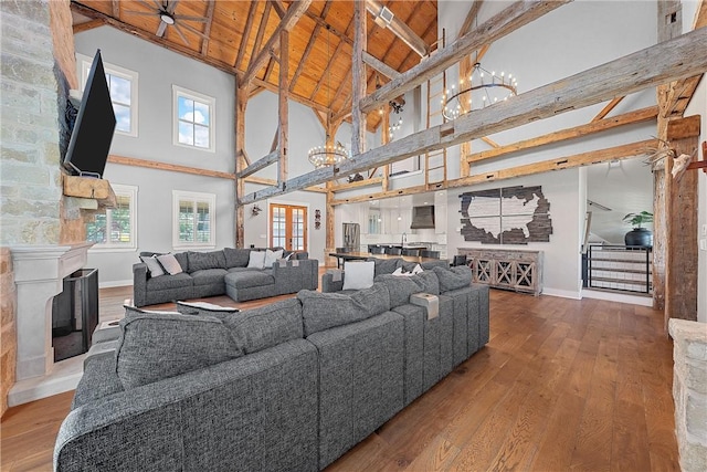 living room with wood ceiling, a stone fireplace, wood-type flooring, high vaulted ceiling, and beam ceiling