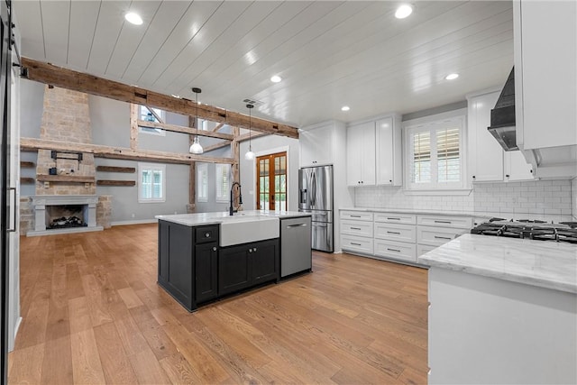 kitchen with decorative light fixtures, beam ceiling, white cabinetry, a kitchen island with sink, and stainless steel appliances