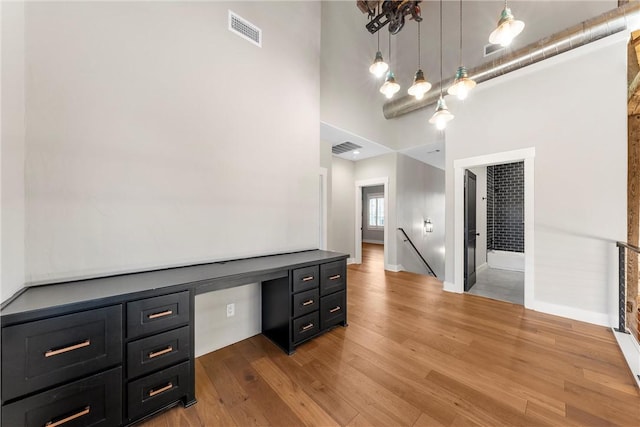 office area featuring a towering ceiling and hardwood / wood-style floors