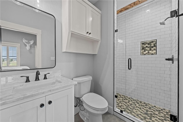 bathroom with a shower with shower door, vanity, and toilet