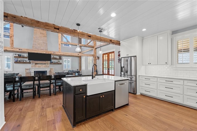 kitchen with appliances with stainless steel finishes, decorative light fixtures, beam ceiling, white cabinets, and sink