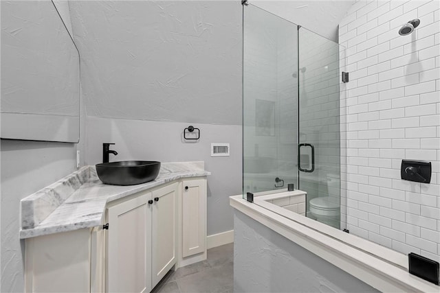 bathroom featuring toilet, vanity, vaulted ceiling, and a shower with door