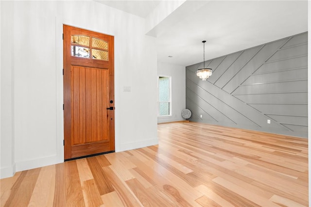 entrance foyer with wood walls, light hardwood / wood-style floors, and a chandelier