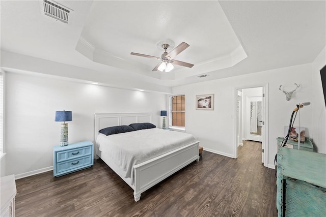 bedroom featuring ceiling fan, dark hardwood / wood-style flooring, and a tray ceiling