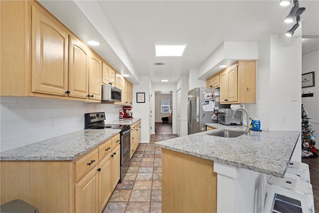 kitchen featuring kitchen peninsula, light stone countertops, light brown cabinets, and appliances with stainless steel finishes