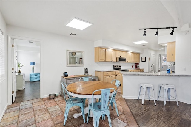 dining space with hardwood / wood-style floors, track lighting, and sink