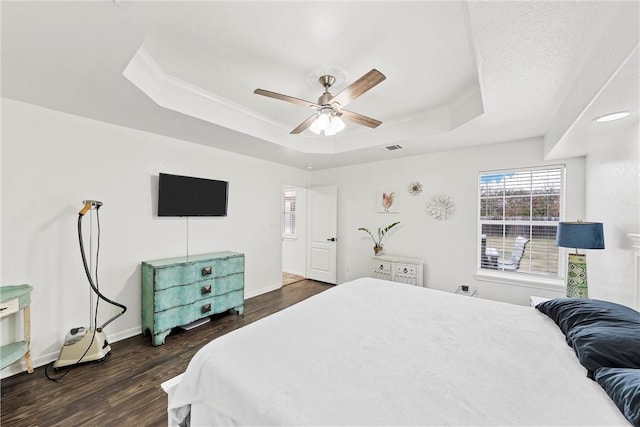 bedroom featuring a tray ceiling, ceiling fan, and dark wood-type flooring