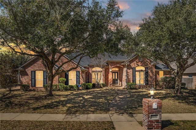 ranch-style home with brick siding and a lawn