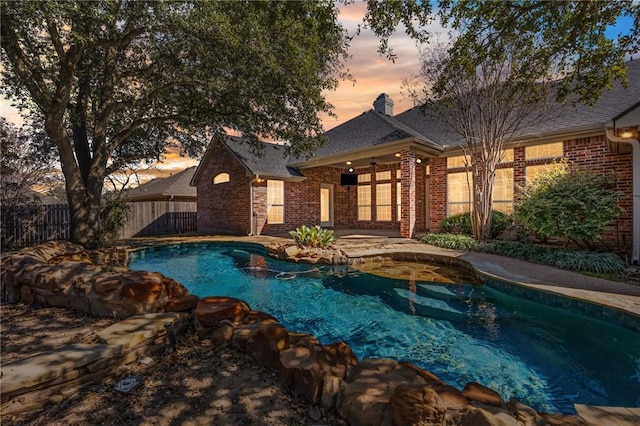 pool at dusk featuring a fenced in pool and fence