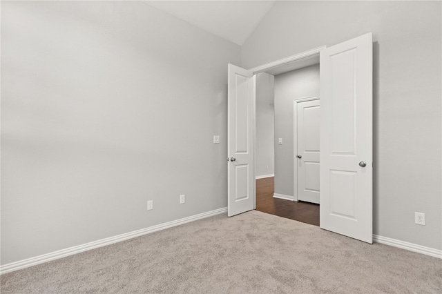 unfurnished bedroom featuring dark carpet and vaulted ceiling