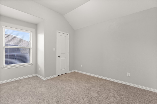 carpeted spare room featuring vaulted ceiling