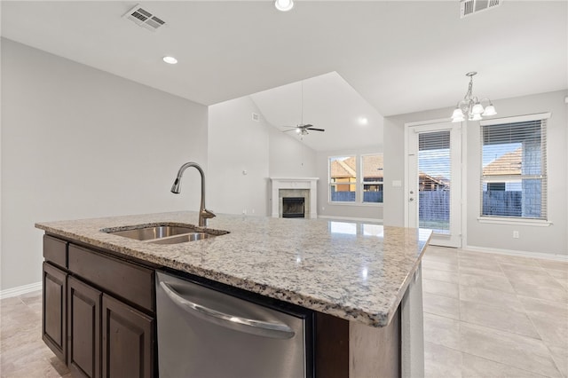 kitchen with stainless steel dishwasher, ceiling fan with notable chandelier, sink, a center island with sink, and lofted ceiling